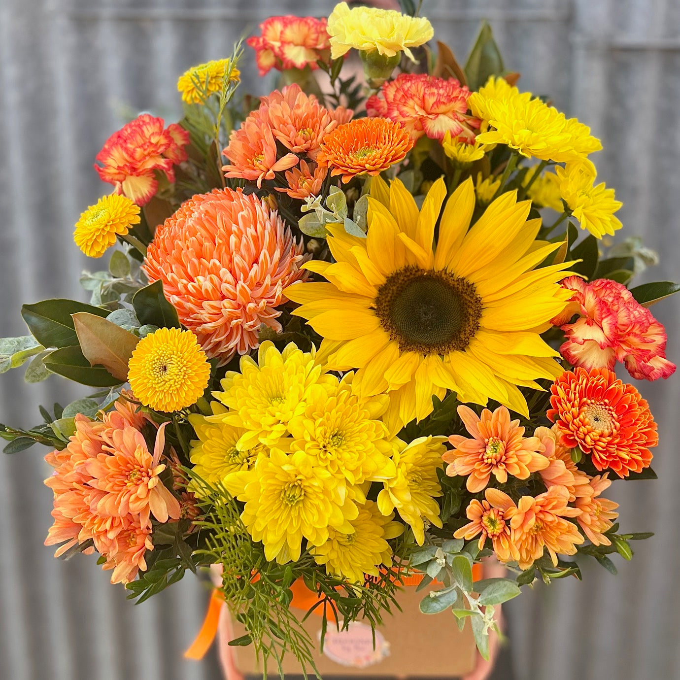 A yellow and orange floral arrangement in a box